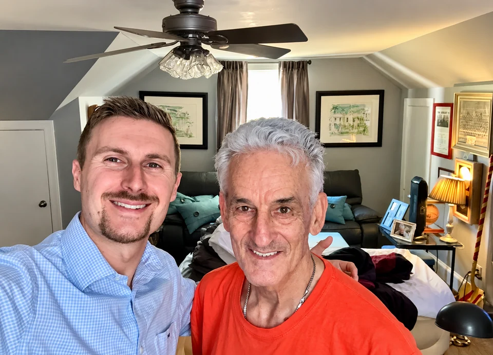 Preston beside a smiling man in an orange shirt at home